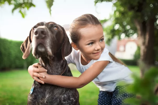 Mädchen umarmt Hund auf Wiese
