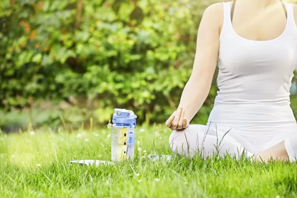 Eine Frau macht auf einer Wiese eine Yoga-Einheit.